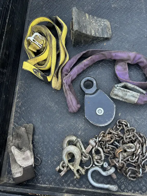 Towing straps, chains, and recovery equipment laid out on a truck bed